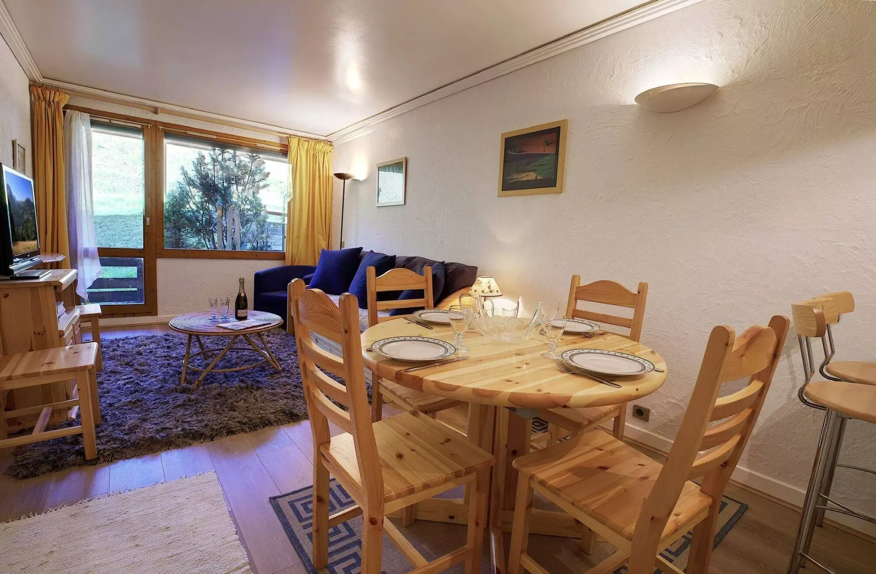 A dining area with a wooden table and chairs beside a living room seating area.