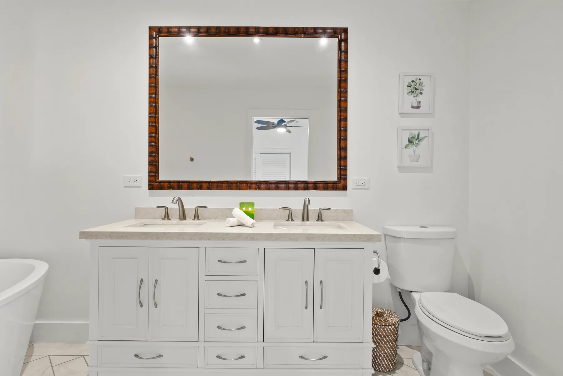Un baño luminoso con un tocador largo, un espejo grande y un inodoro.