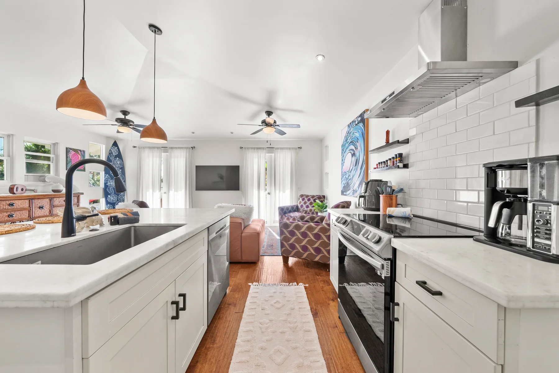 A bright open-plan kitchen with a central island and living area beyond.