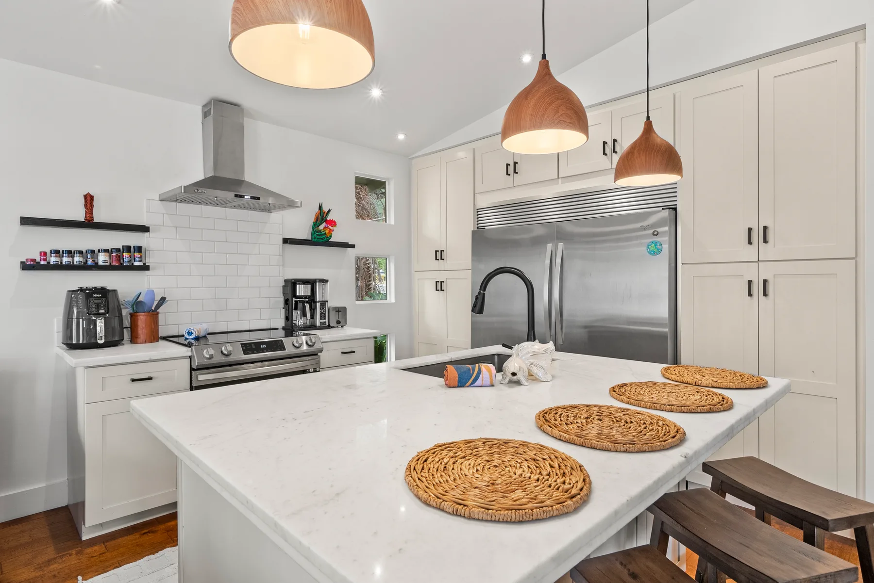 Una cocina luminosa con una isla grande y electrodomésticos de acero inoxidable.