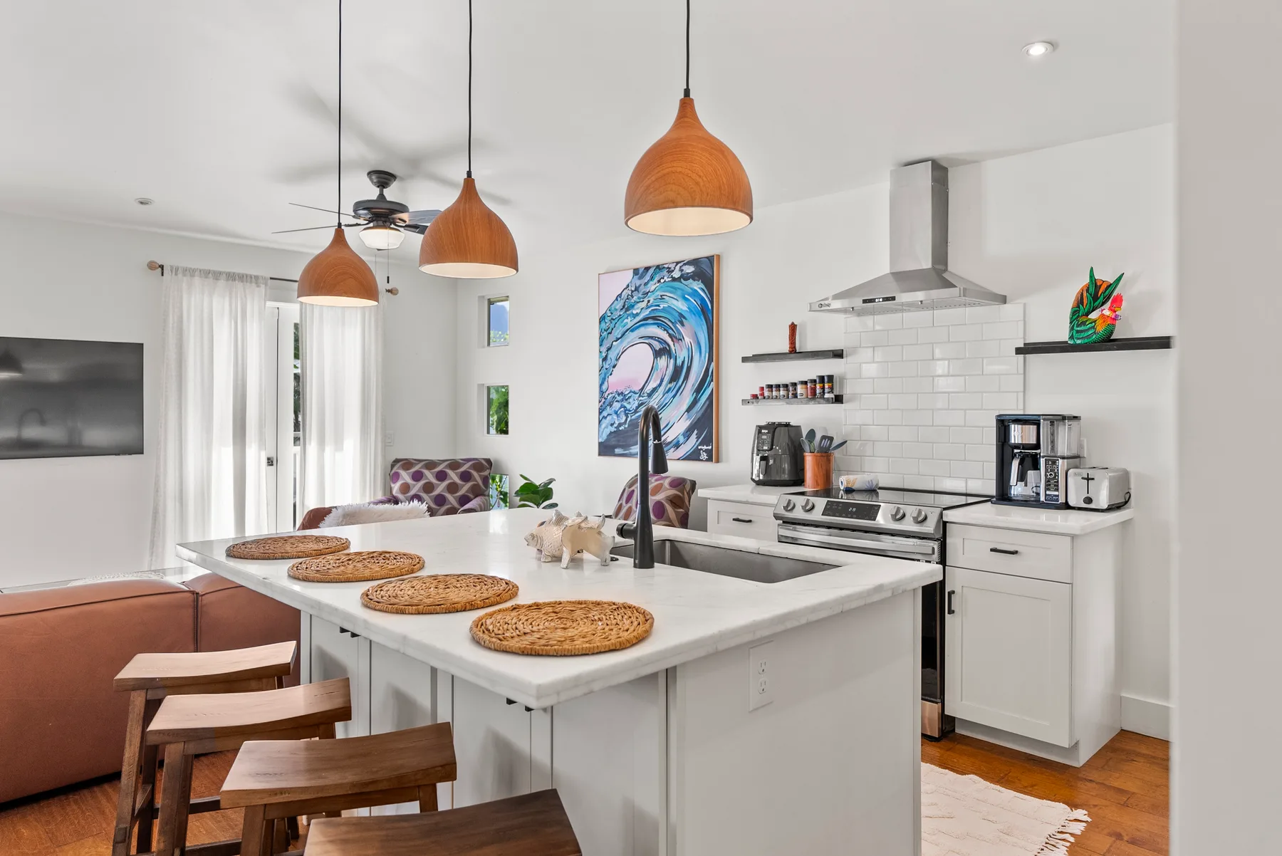 Una cocina y comedor de concepto abierto con una isla grande y lámparas colgantes.