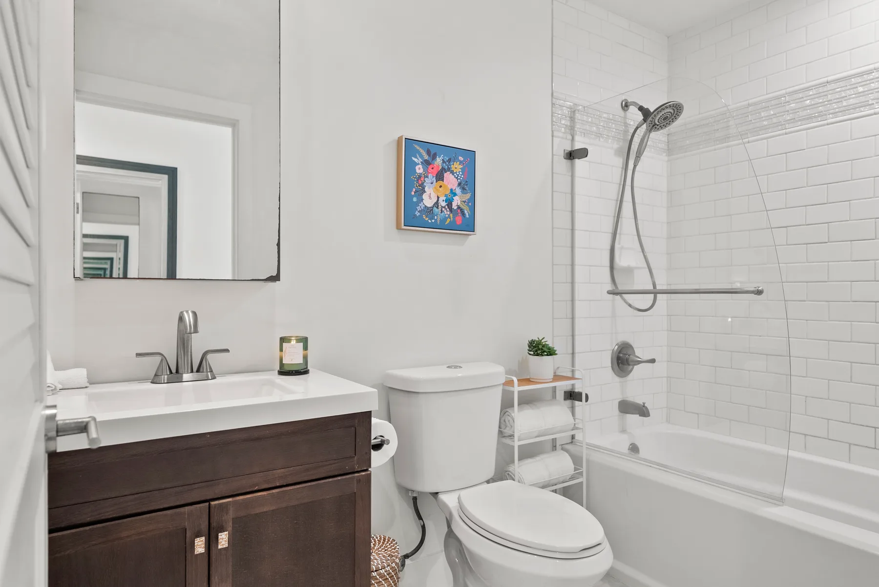 Un baño luminoso con tocador, inodoro y ducha revestida de azulejos.