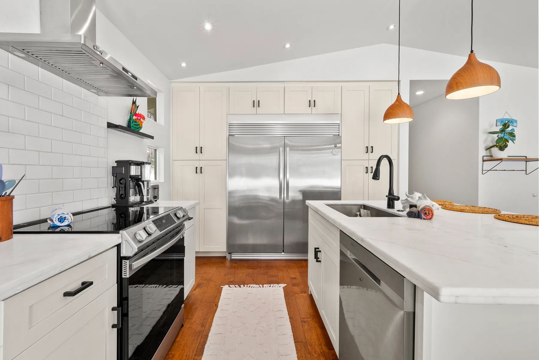 Una cocina luminosa con una isla central, electrodomésticos de acero inoxidable y gabinetes blancos.