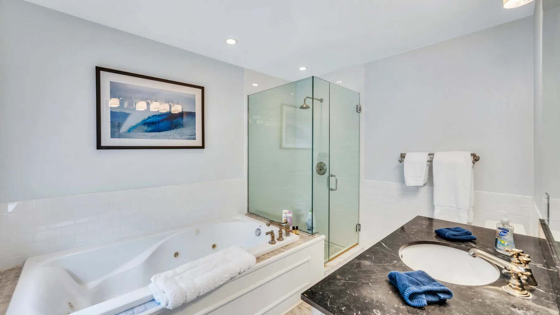 A bathroom with a bathtub, glass shower, and sink.