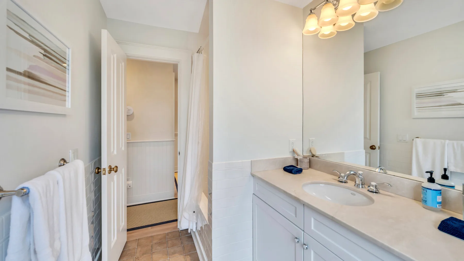 A bathroom vanity with a sink and mirror sits beside an open doorway.