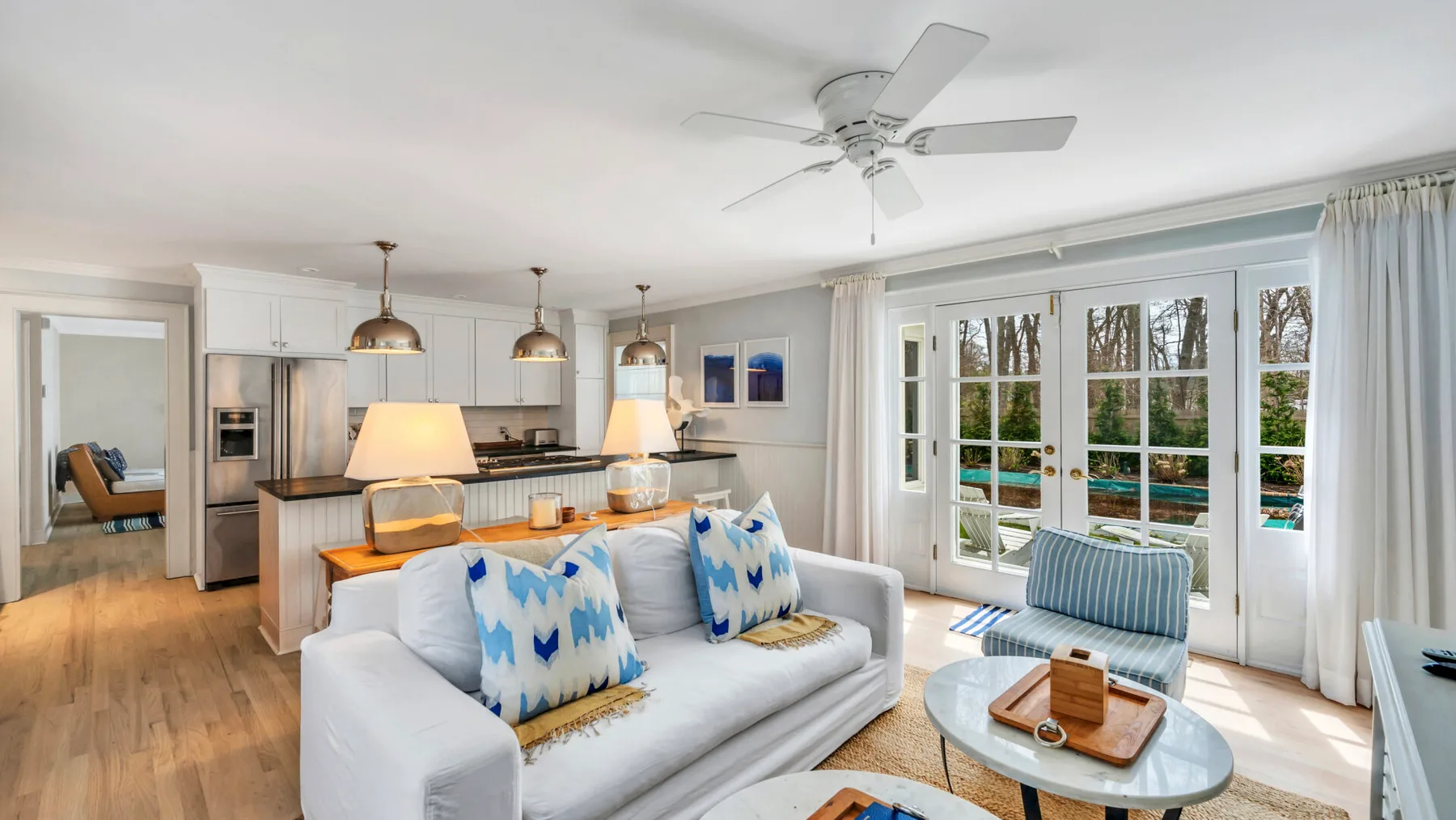 A bright living room with a sofa, an open kitchen, and large glass doors.