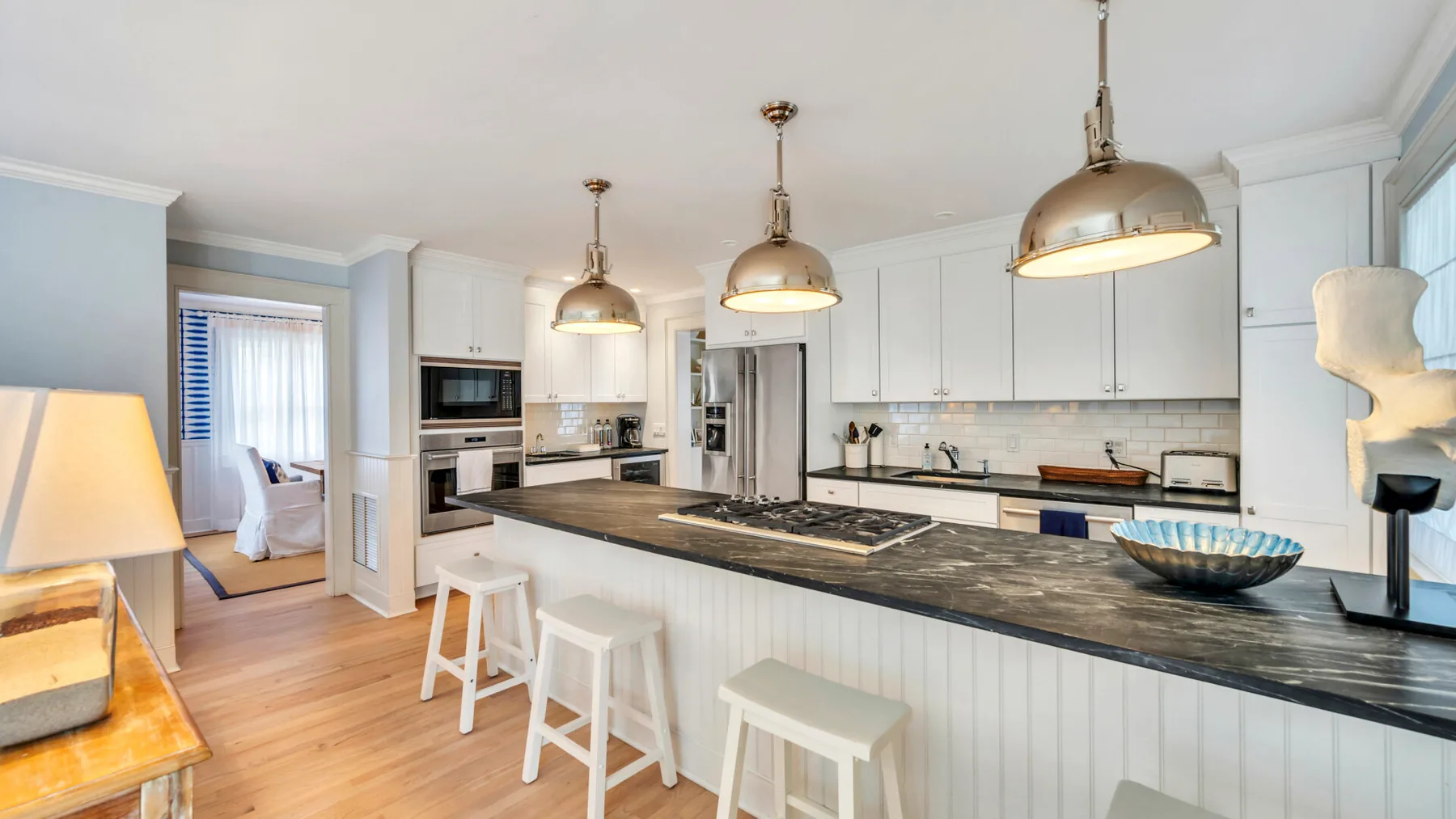 A bright kitchen with a long island and pendant lights.