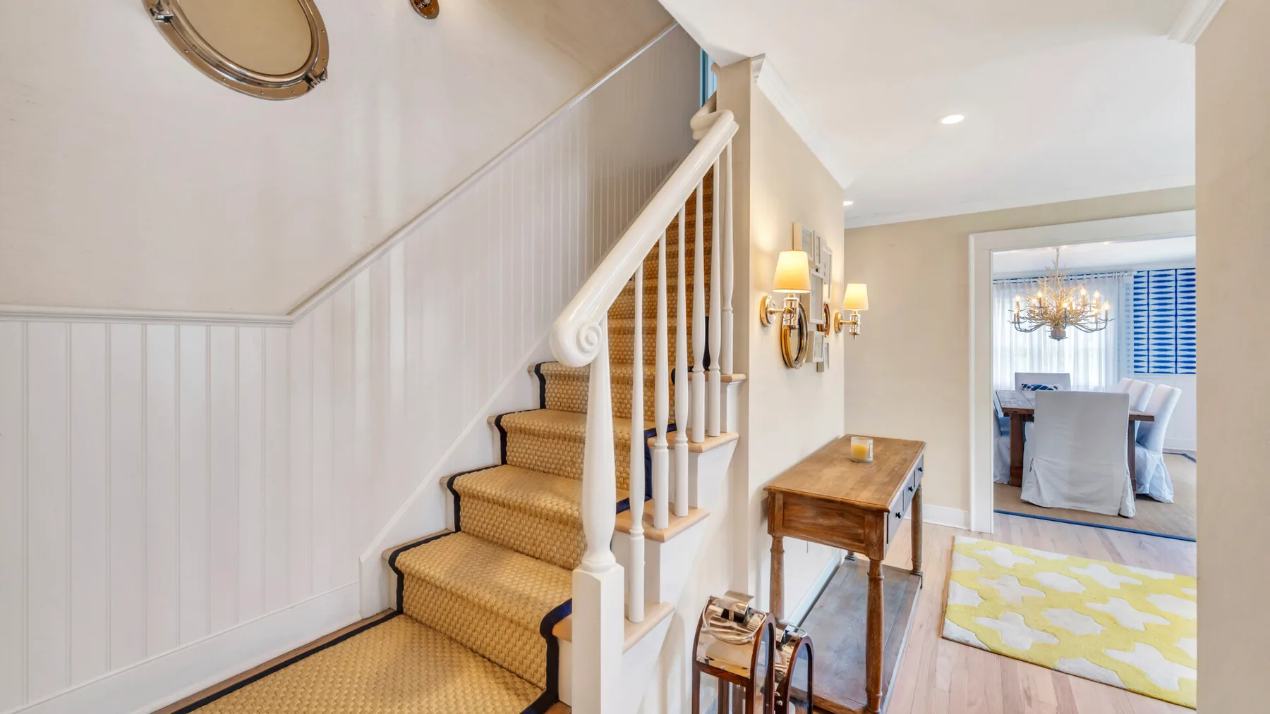 An interior hallway with a carpeted staircase and a wooden console table.
