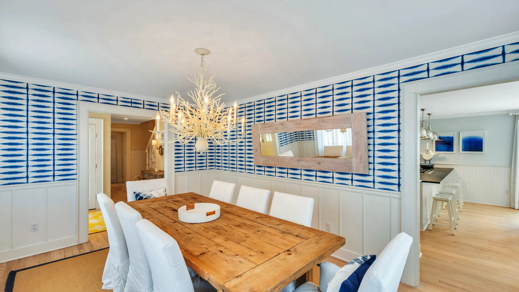 A dining room with a large wooden table and blue-and-white patterned walls.