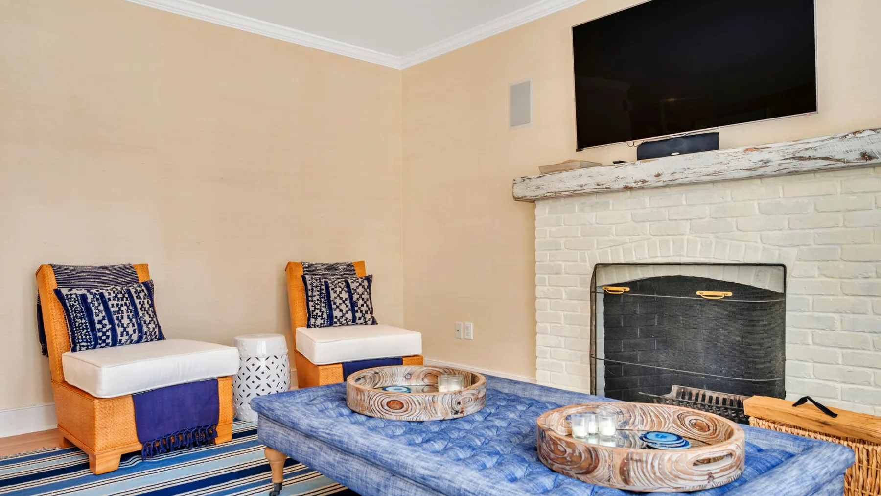 A living room with two blue-cushioned seats and a fireplace.