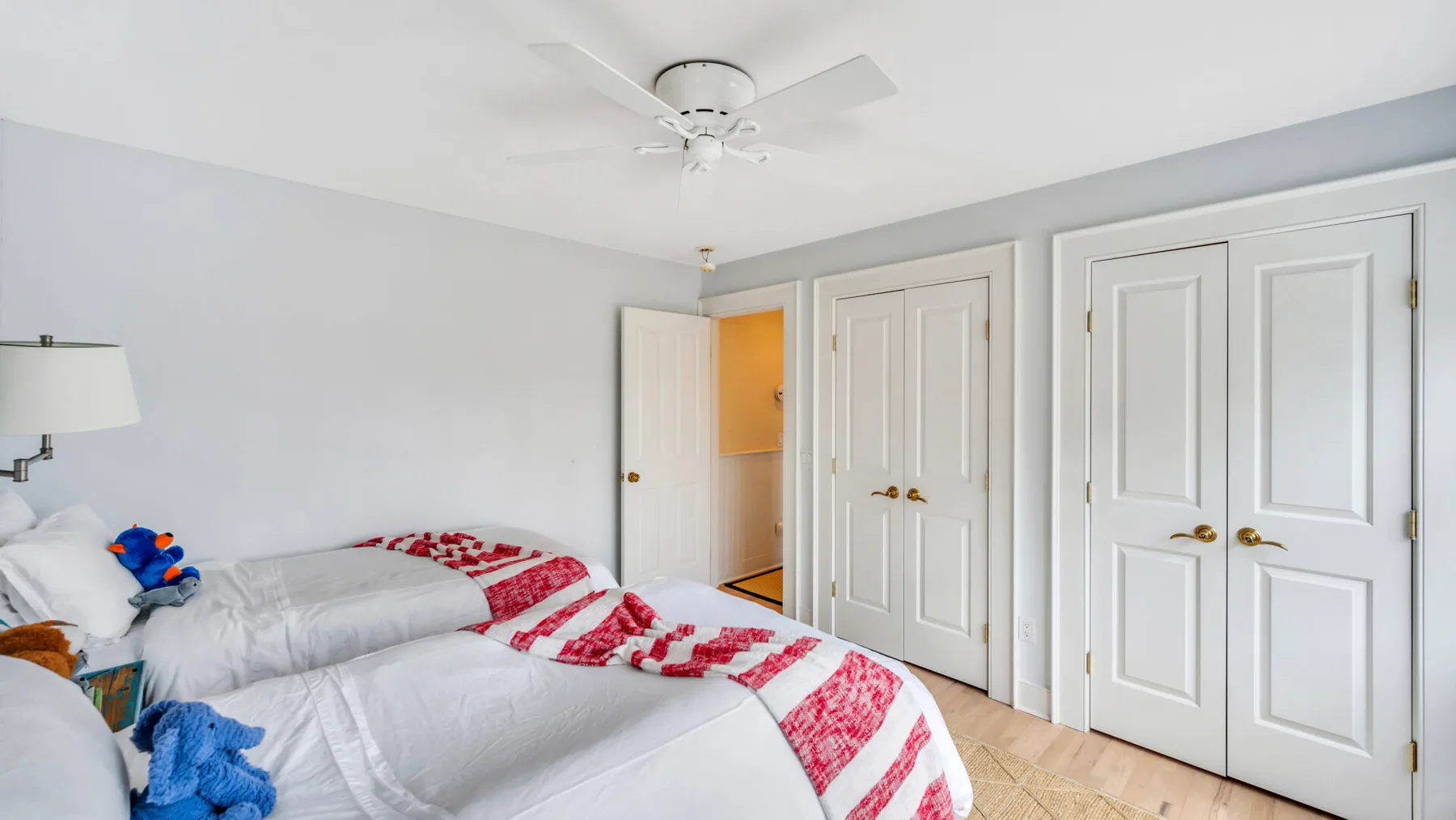 A bright bedroom with beds and white closet doors.