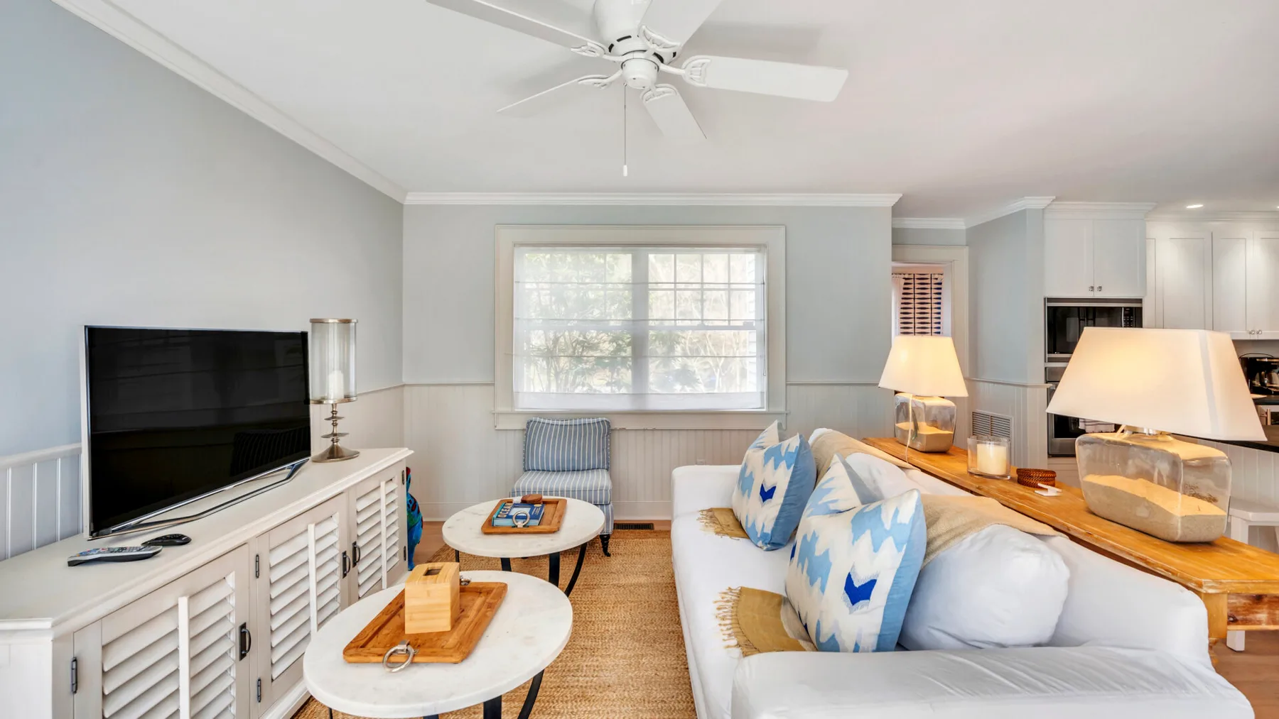 A bright living room with seating, a television, and a large window.