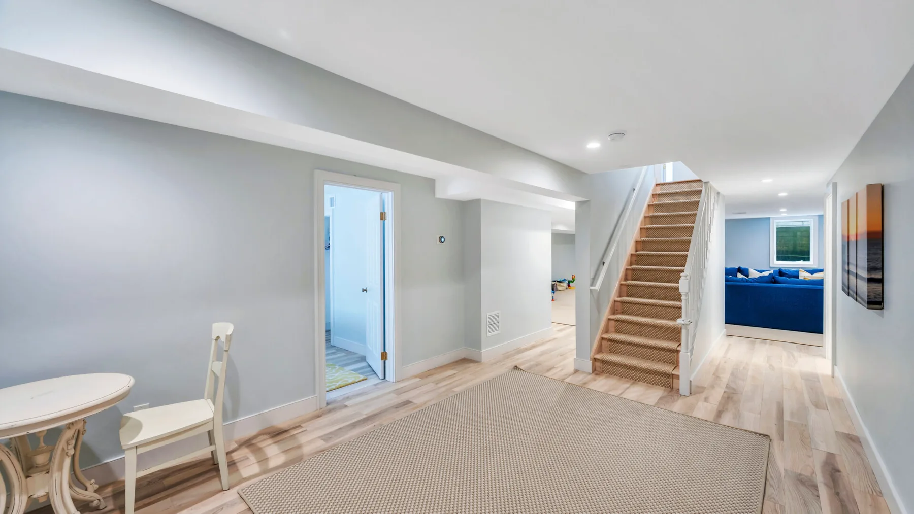 A bright living area with a staircase and a blue sofa in the background.