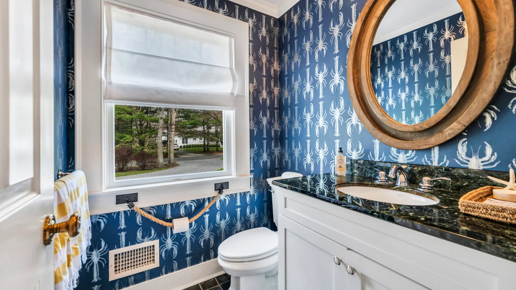A bathroom with a toilet, vanity, and patterned blue walls.