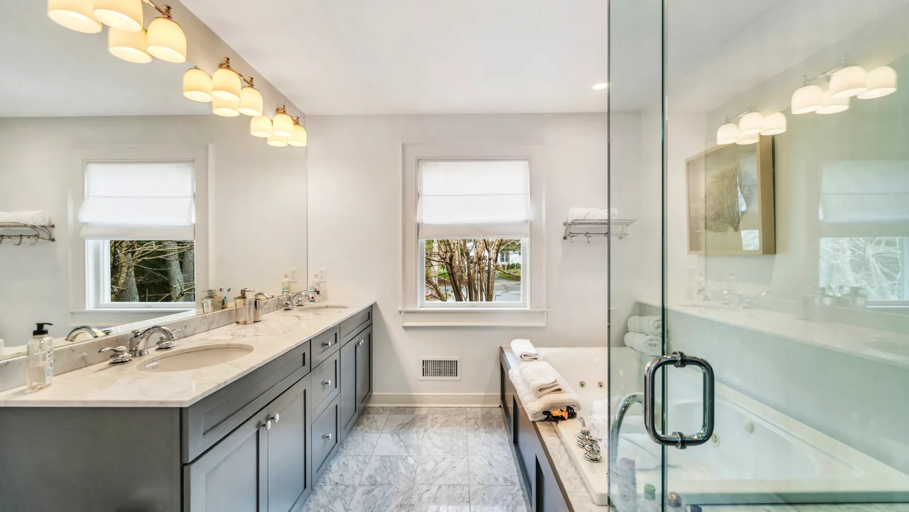 A bright bathroom with a double vanity and a glass-enclosed shower.