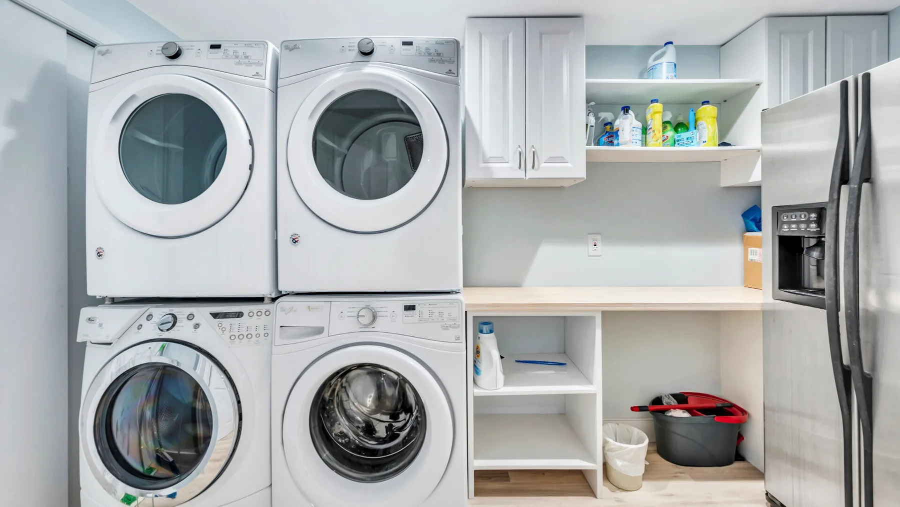 A laundry room with stacked washing machines and a countertop.