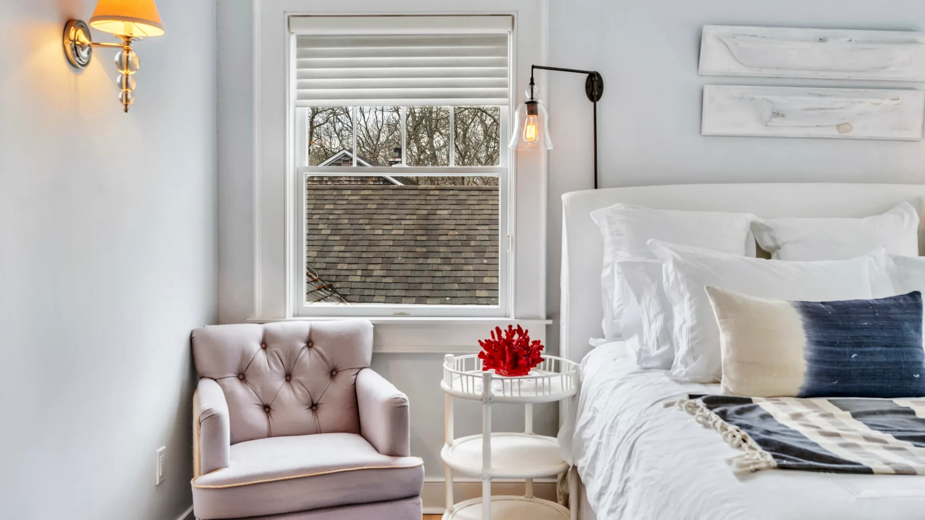 A bright bedroom with a bed, tufted seating, and a small round table.
