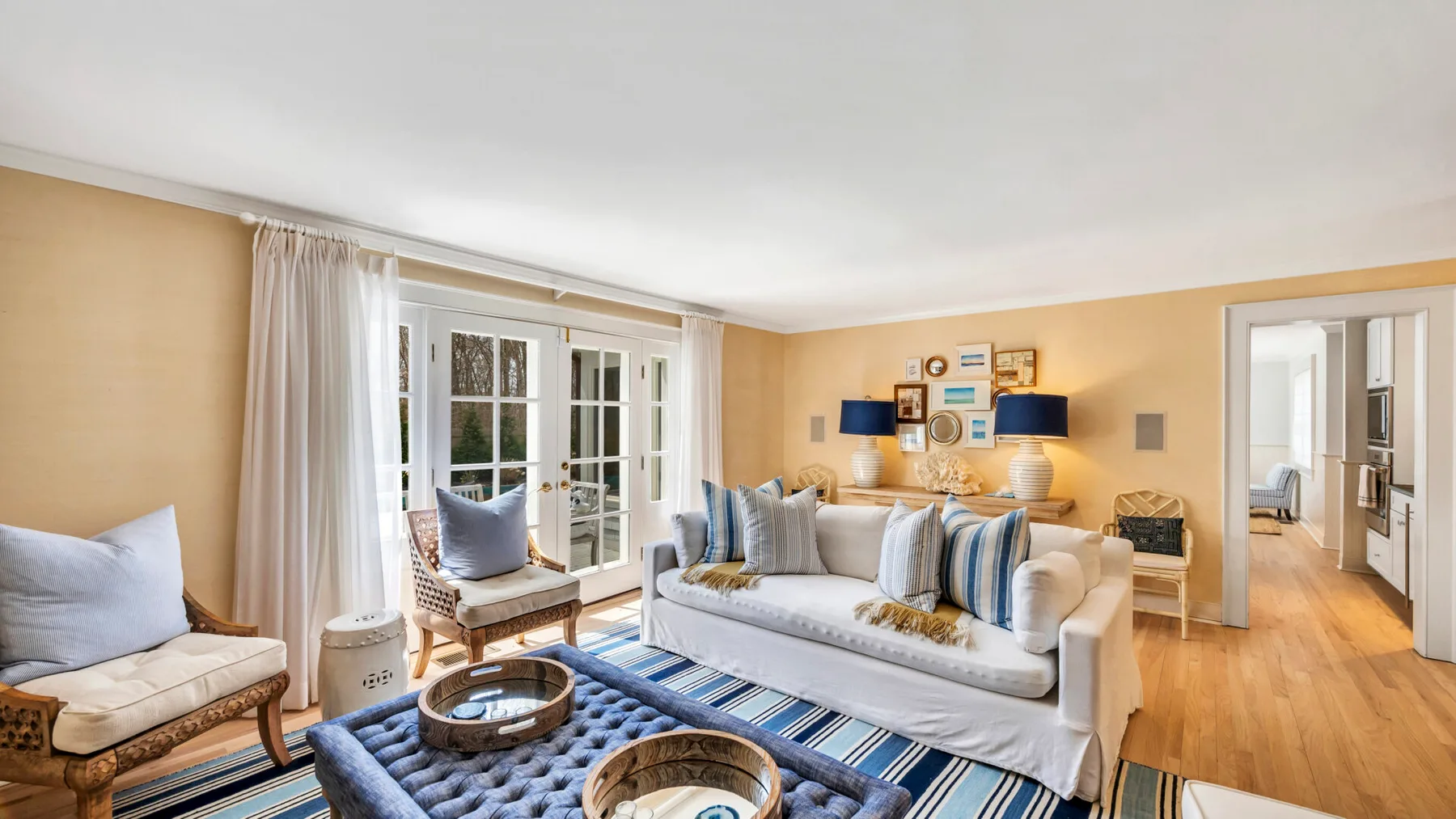 A bright living room with seating, a rug, and large windows.