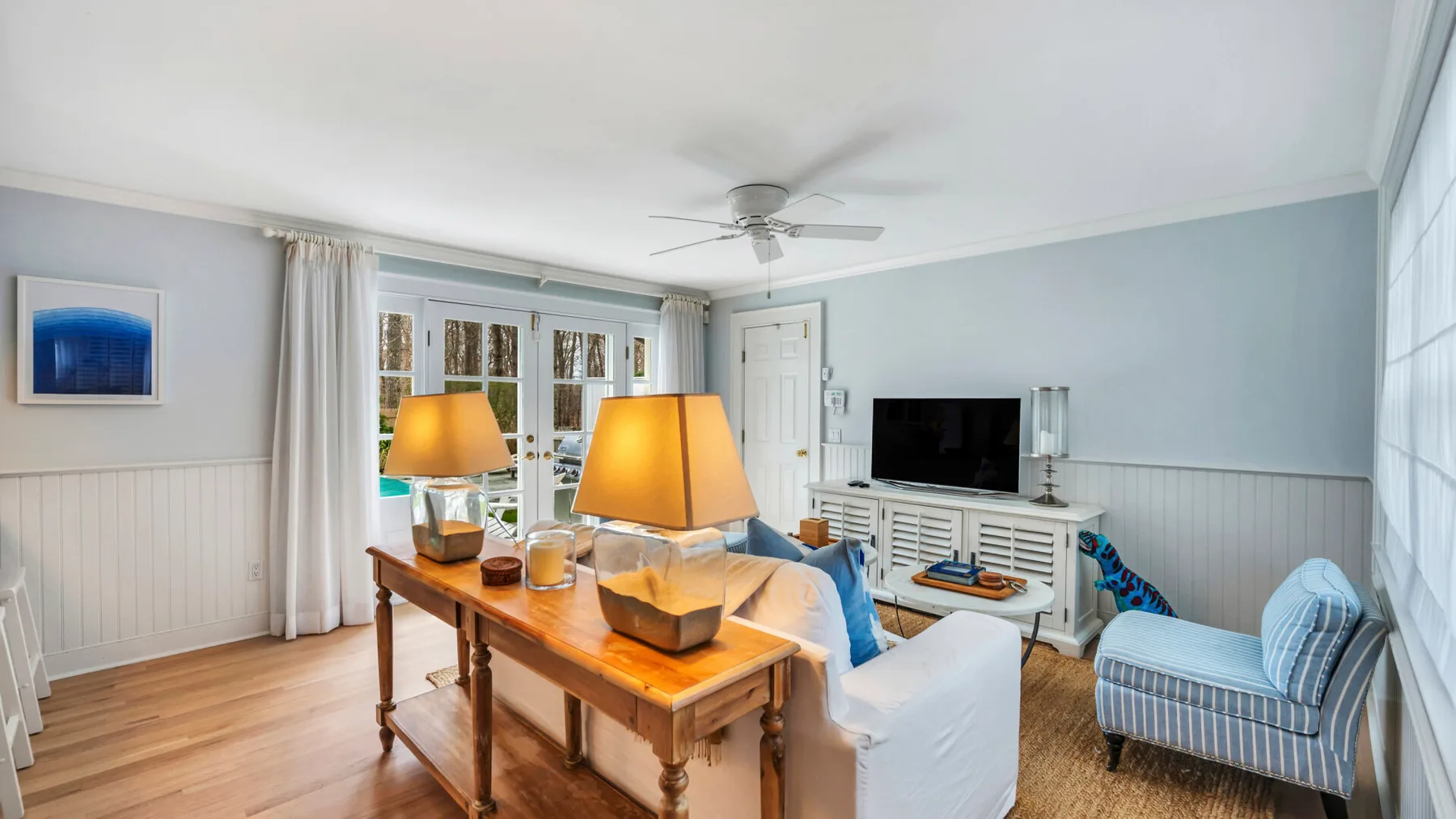 A bright living room with a wooden coffee table, seating, and a television.