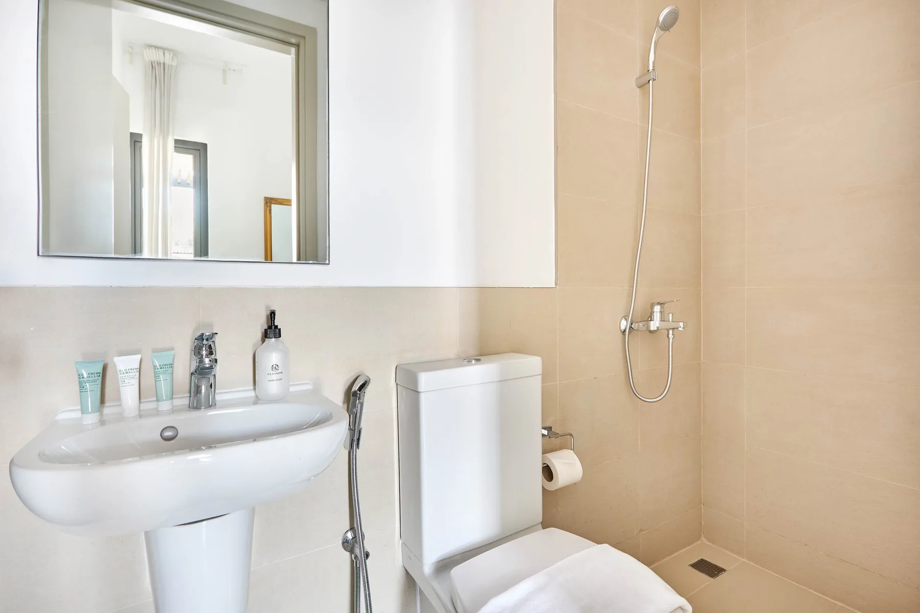 Un baño luminoso con un lavabo de pared y una ducha.