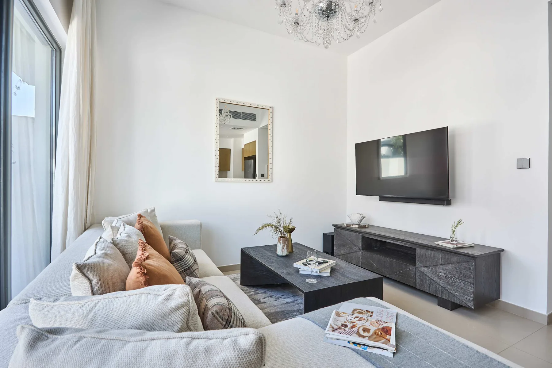 Una sala de estar luminosa con asientos, un televisor en la pared y una mesa de centro.