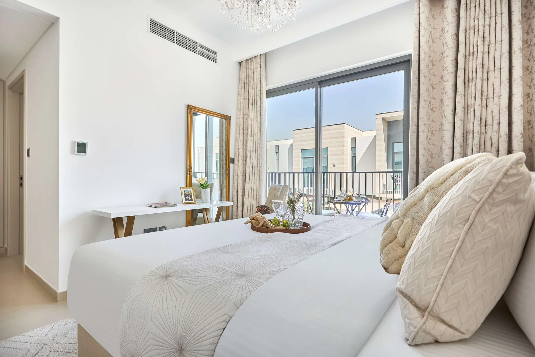 Un dormitorio luminoso con una cama tendida frente a puertas corredizas de vidrio.