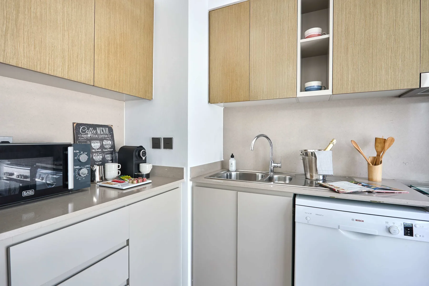 Una cocina luminosa con gabinetes de madera clara, encimeras y un fregadero.
