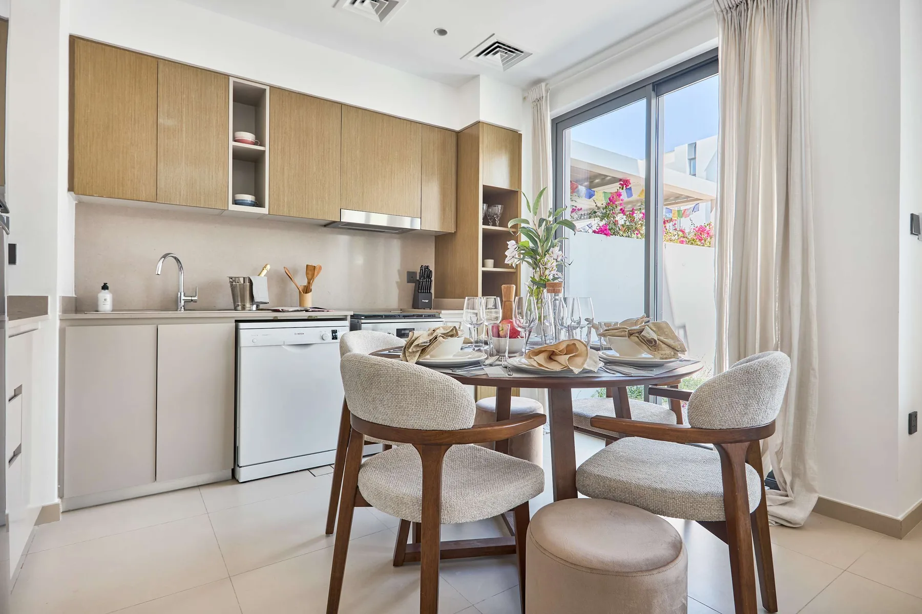 Comedor junto a una cocina, con una mesa puesta cerca de una ventana grande.