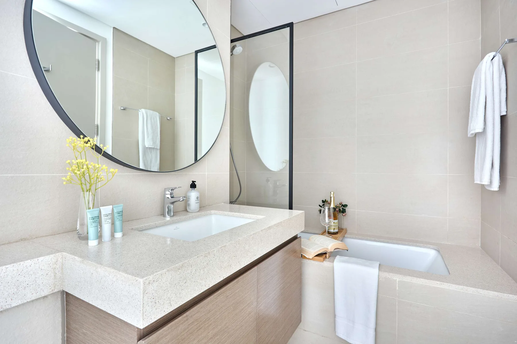 Un baño luminoso con lavabo, espejo grande y bañera.