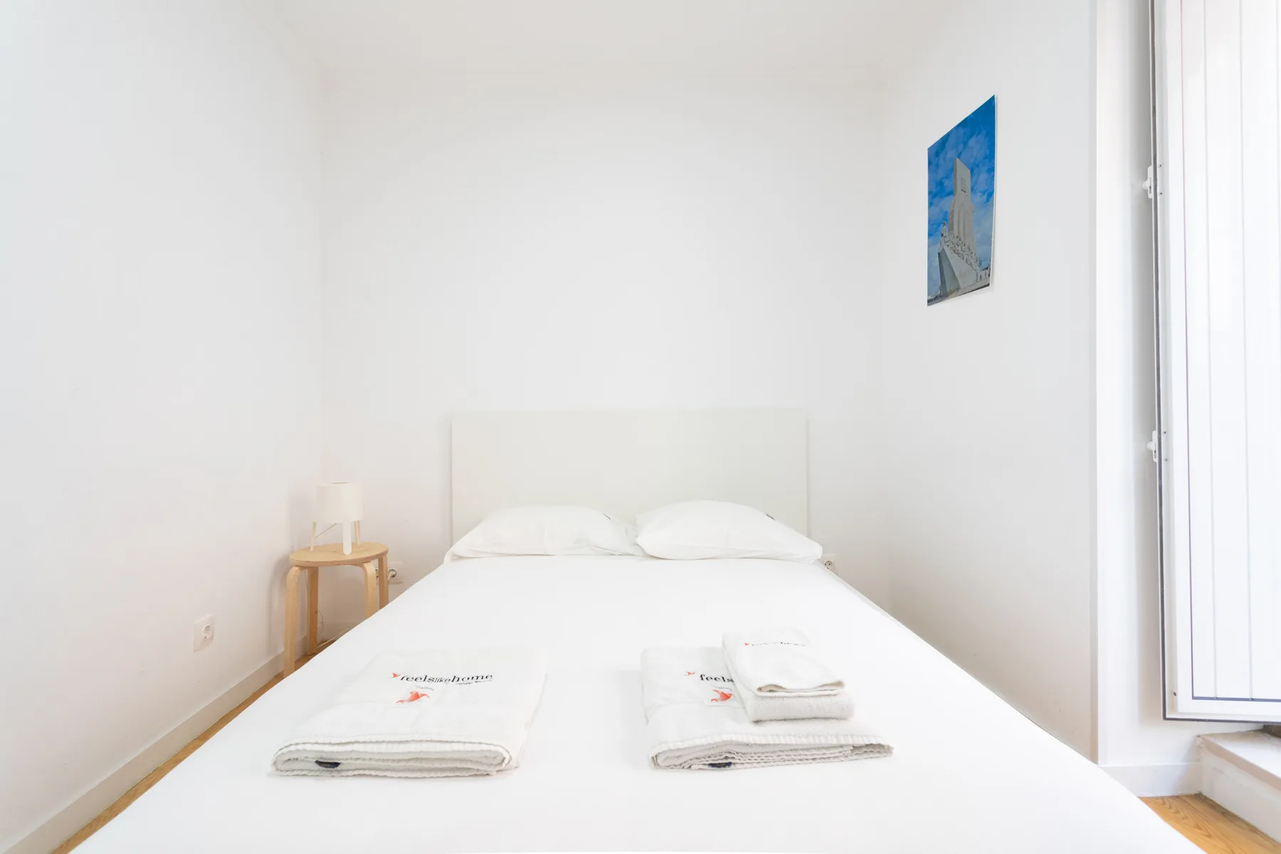 Un dormitorio luminoso con una cama hecha y toallas dobladas.