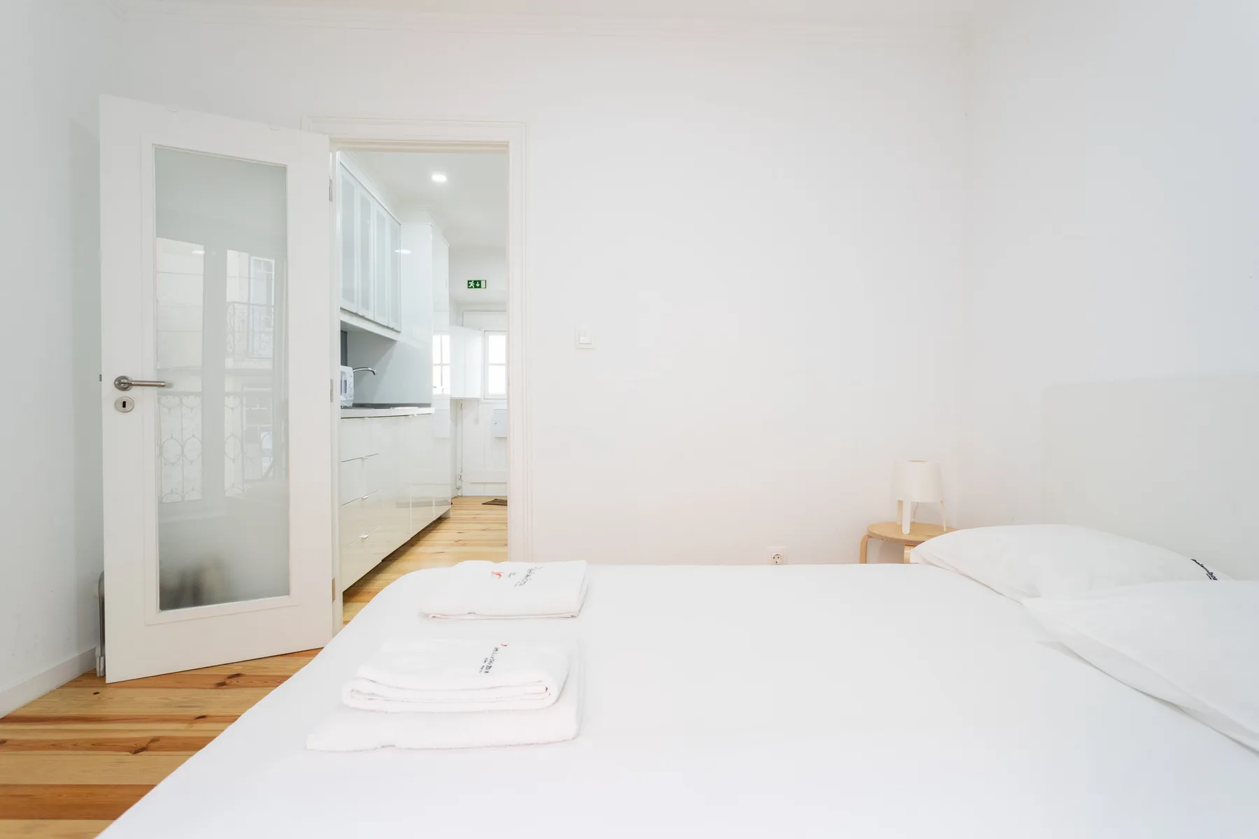 Un dormitorio con una cama y una puerta abierta que da a una cocina.