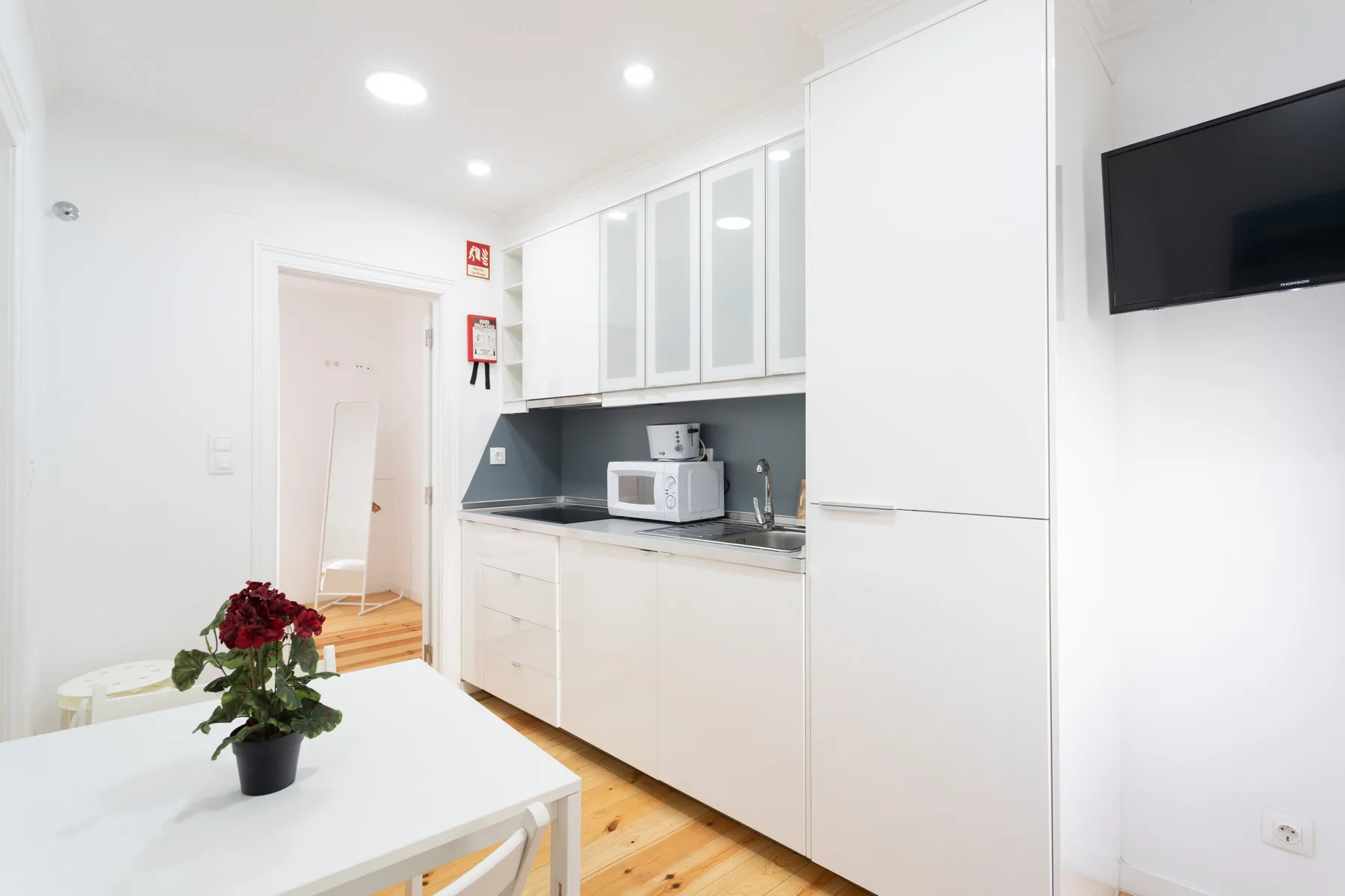 Una cocina luminosa con armarios blancos, una encimera y una pequeña mesa de comedor.