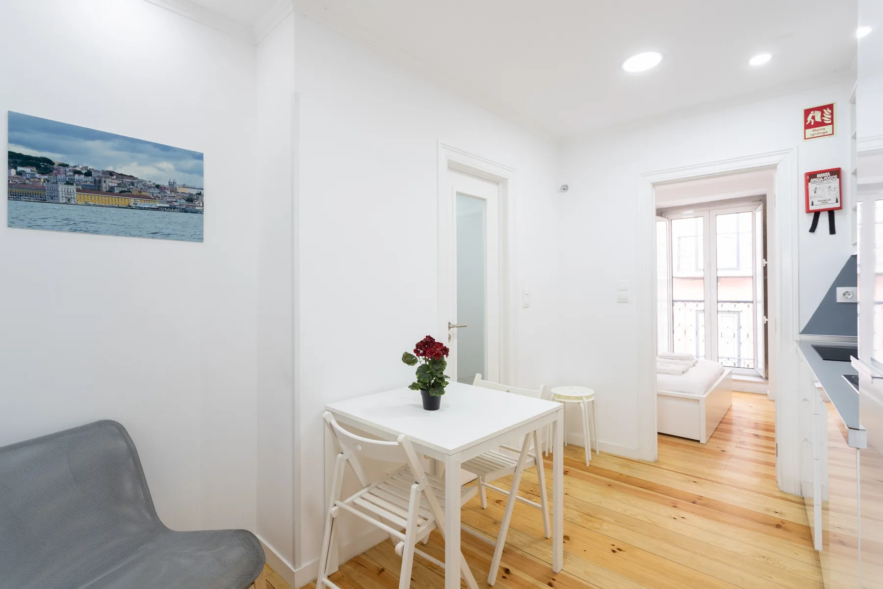 Un comedor luminoso con una mesa blanca y sillas junto a una puerta abierta.