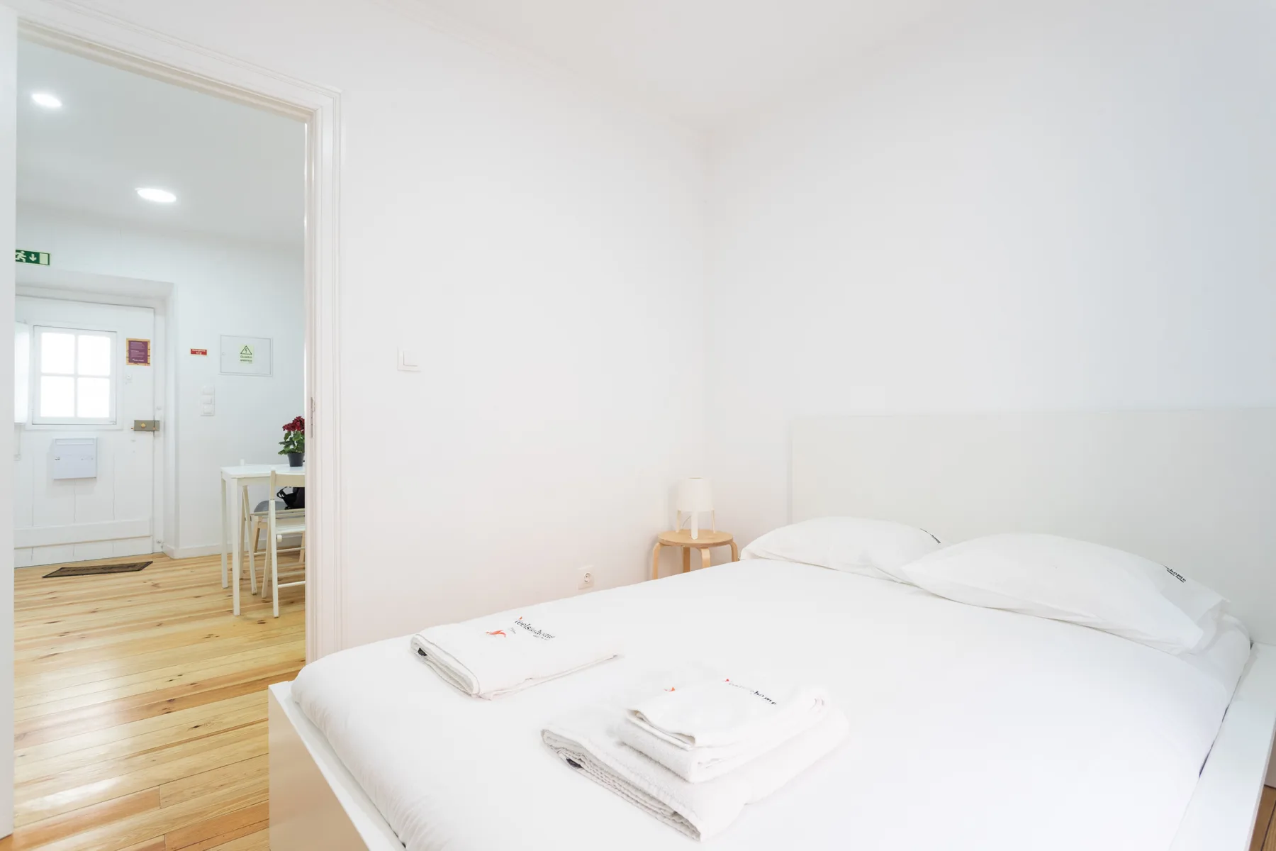 Un dormitorio luminoso con una cama tendida y toallas dobladas.