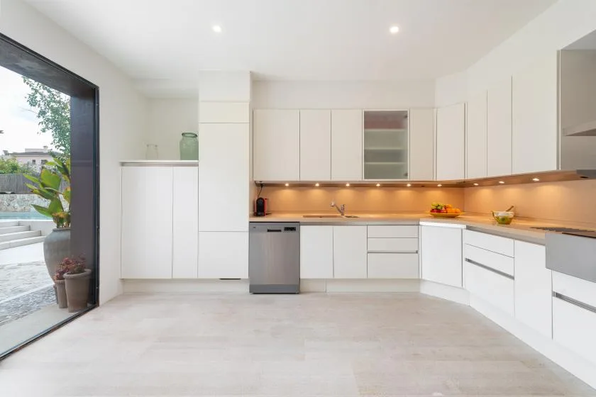 Una cocina moderna y luminosa con gabinetes blancos y una encimera larga.