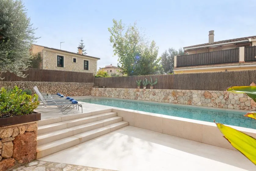 Una piscina exterior con escalones de piedra clara y asientos.