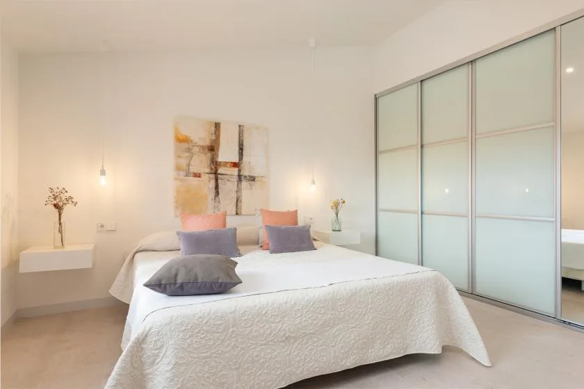 Un dormitorio luminoso con una cama bien tendida y puertas correderas de armario.