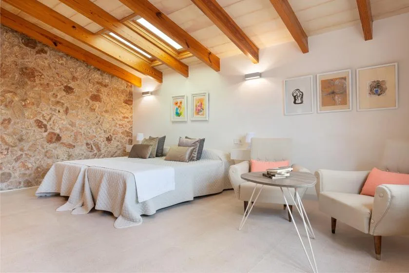 Un dormitorio con dos camas y una pequeña zona de estar bajo vigas de madera vistas.