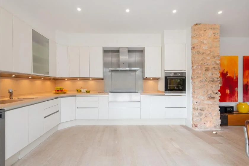 Una cocina moderna y luminosa, con gabinetes blancos y una zona de cocción central.