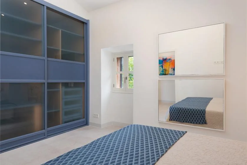 Un dormitorio con una colcha azul estampada junto a un armario empotrado grande.