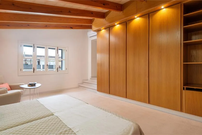 Un dormitorio luminoso con un gran armario de madera y una ventana.