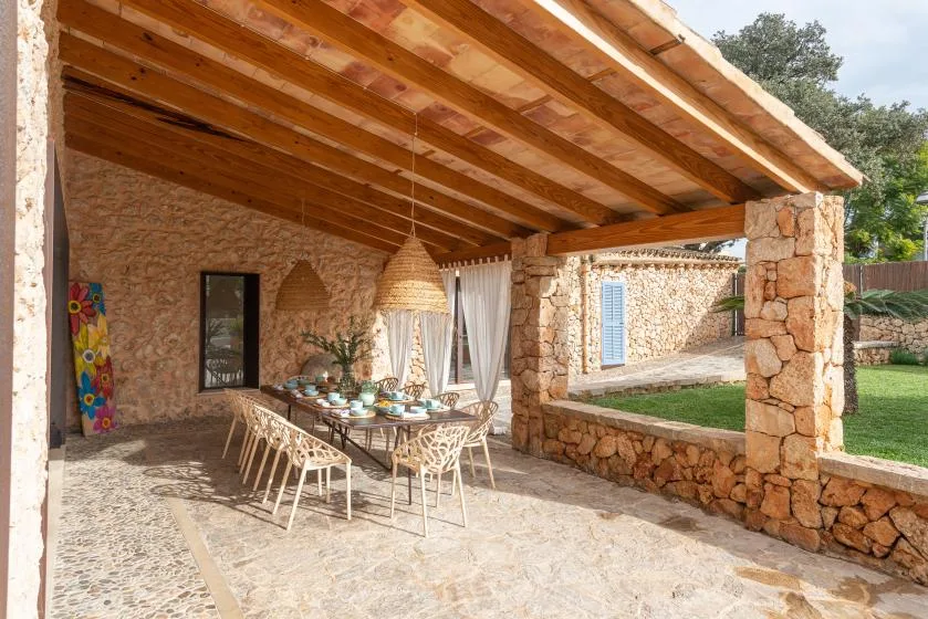 Un patio cubierto de piedra tiene una mesa de comedor bajo un techo de madera.