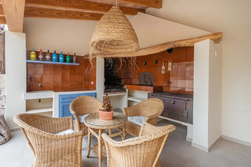 Una cocina rústica y comedor con asientos de mimbre alrededor de una mesa pequeña.