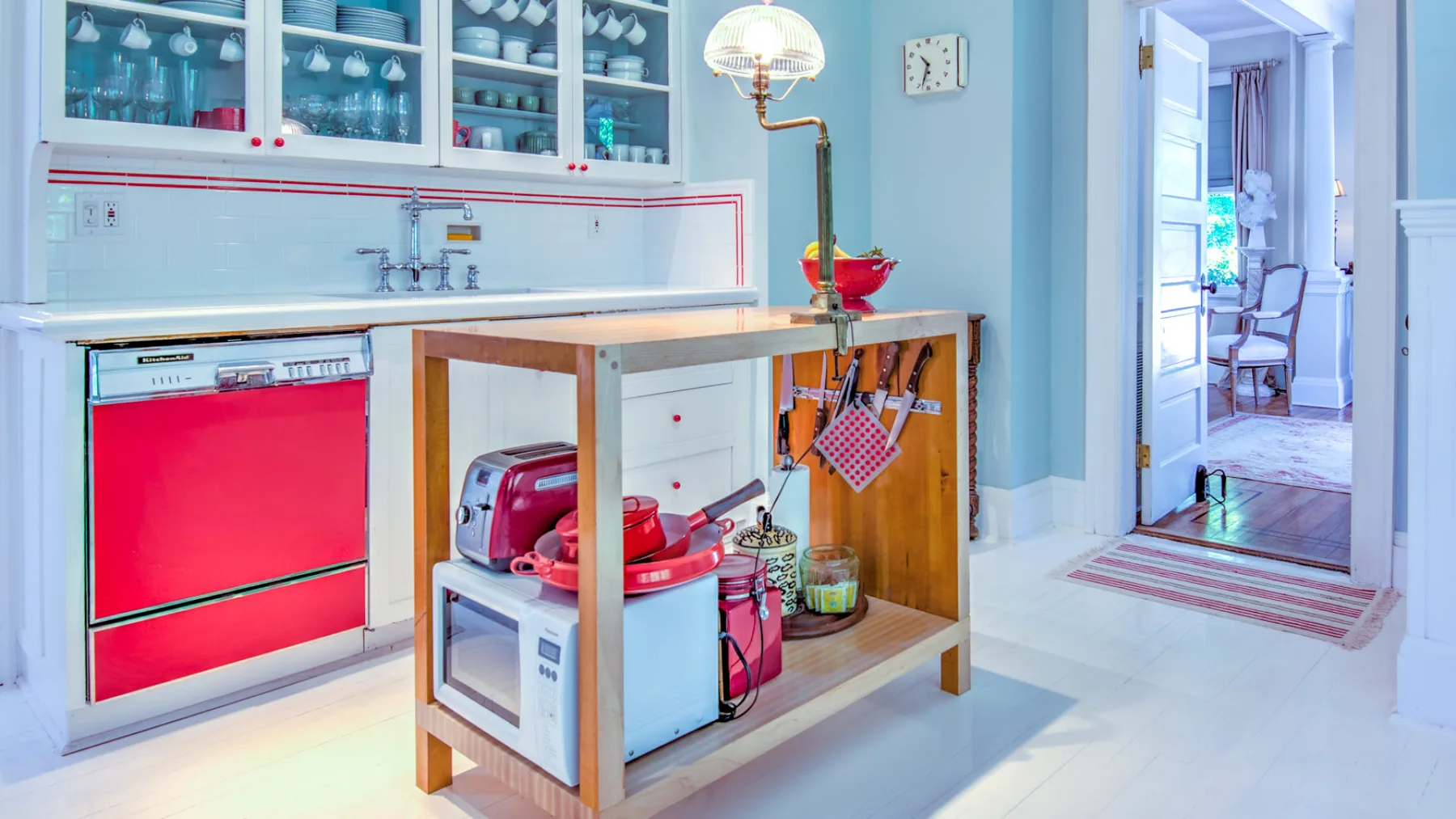 A bright kitchen with glass-front cabinets and a central worktable.