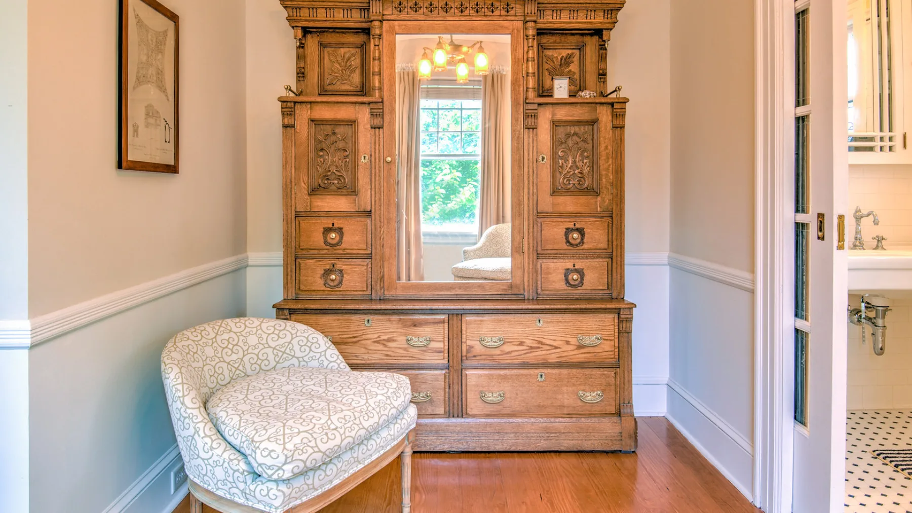 A bedroom features an ornate wooden wardrobe and a patterned upholstered chair.