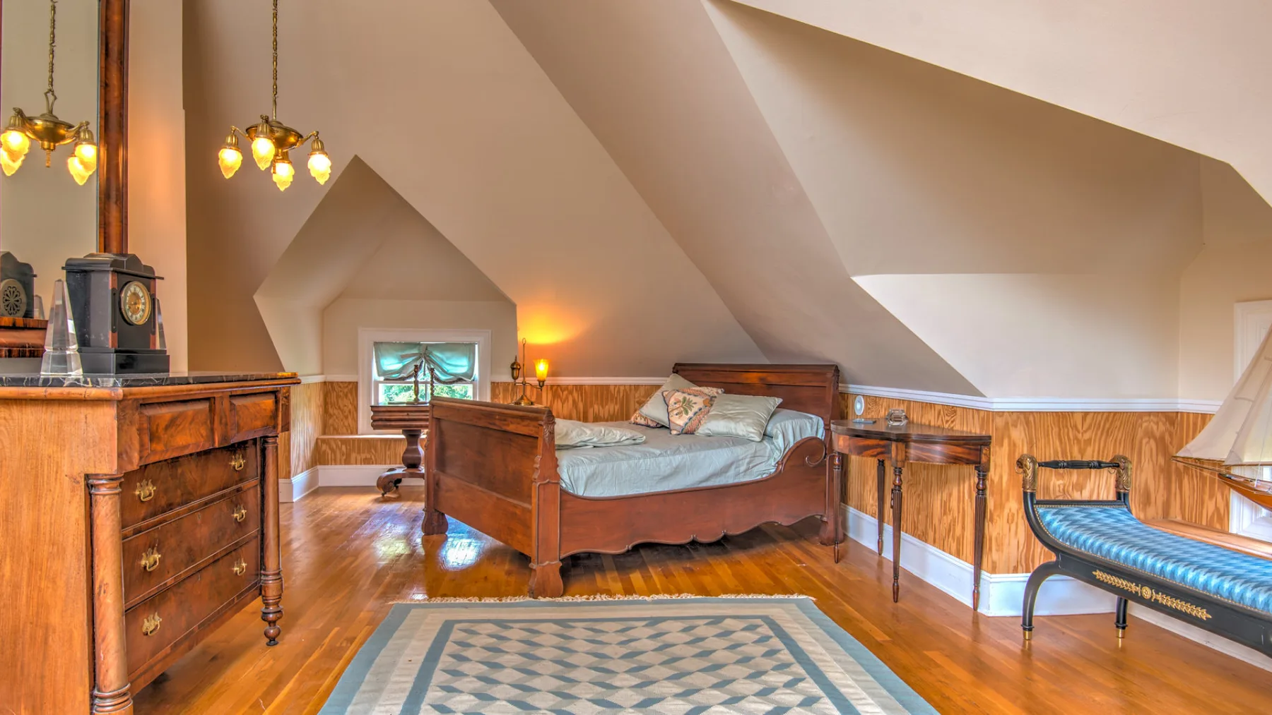 A bedroom with a wooden bed, sloped ceiling, and patterned rug.