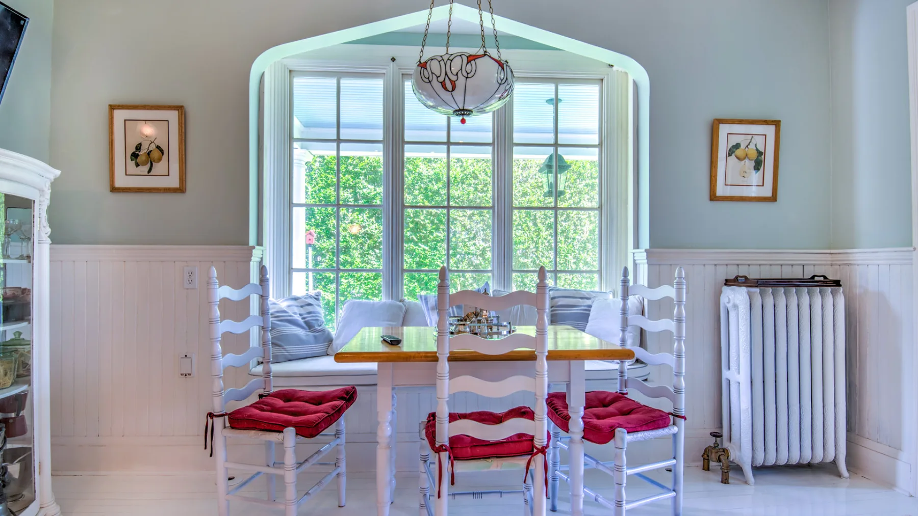 A bright dining area with a table and chairs beside a large window.