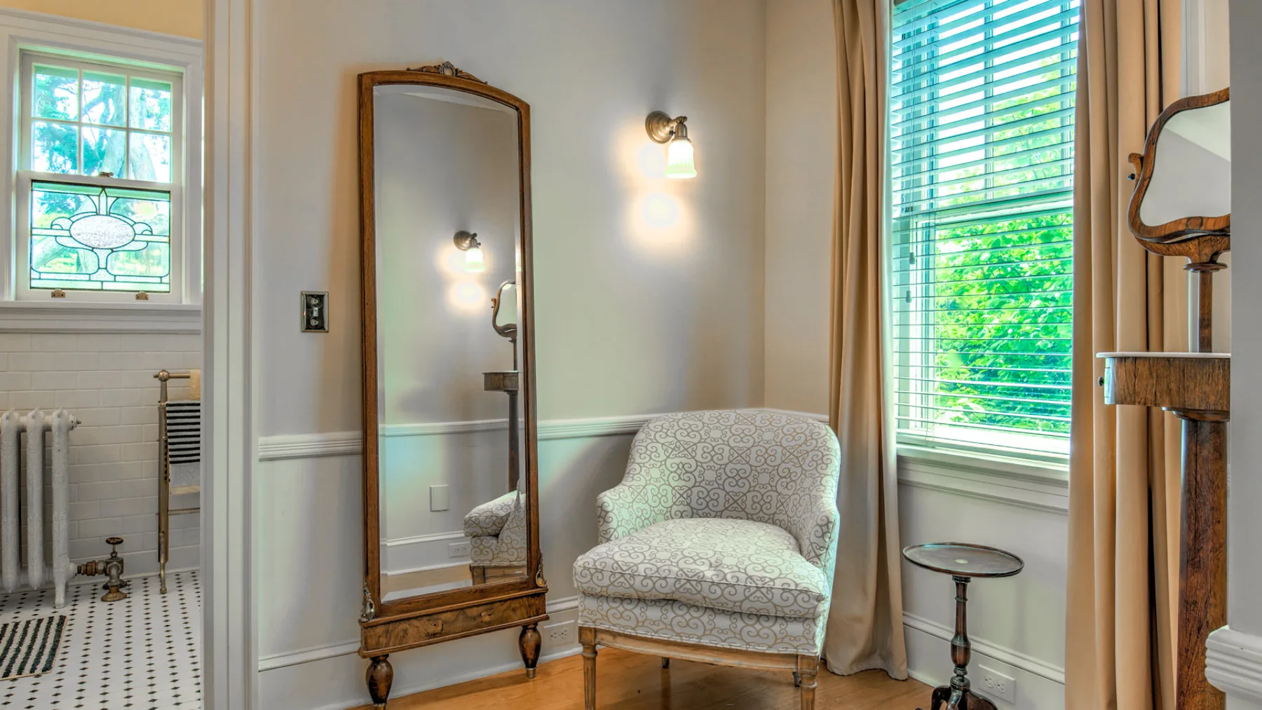 A bright sitting area with a patterned armchair beside tall windows.