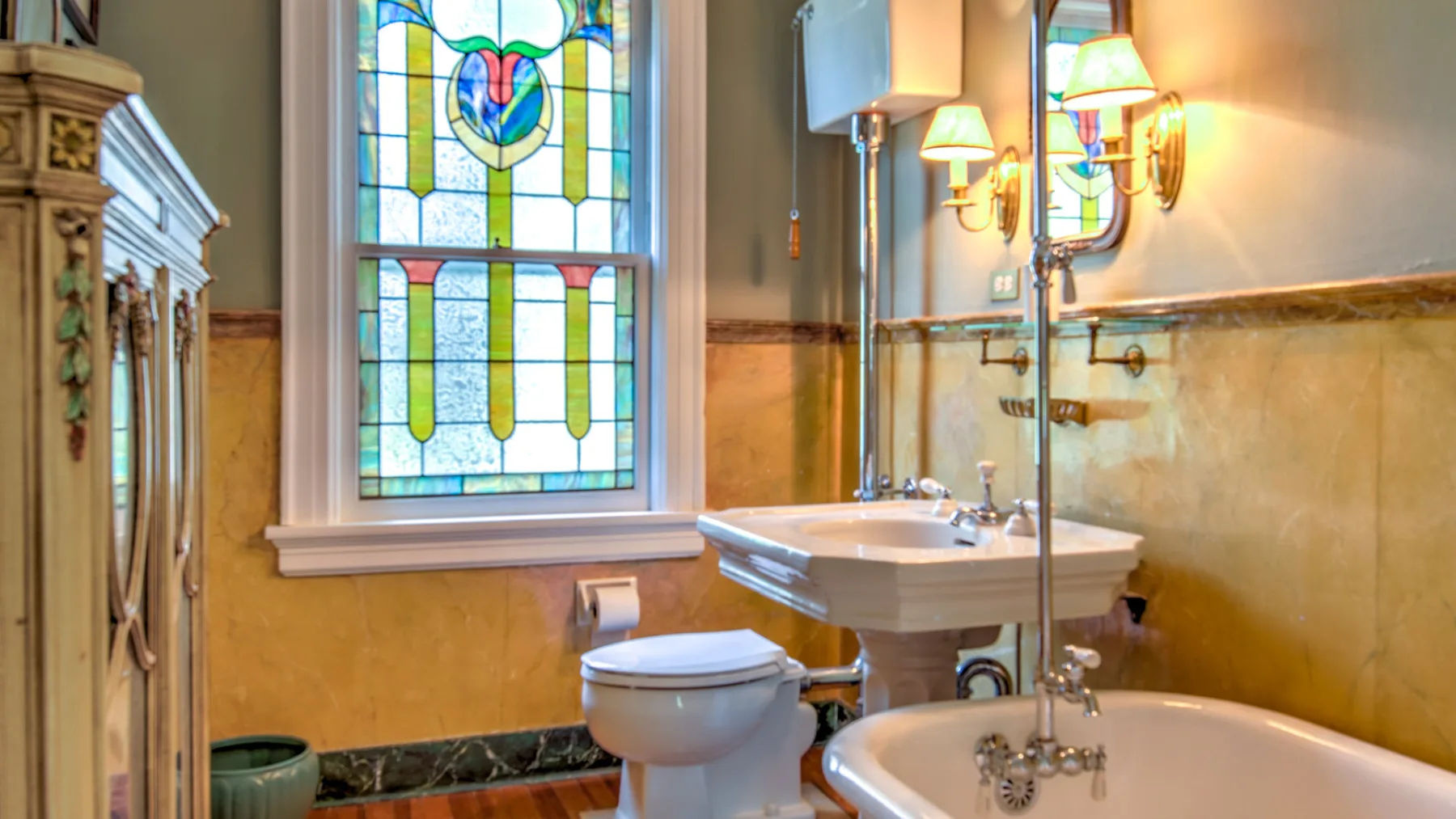 A bathroom with a bathtub, sink, toilet, and stained-glass window.