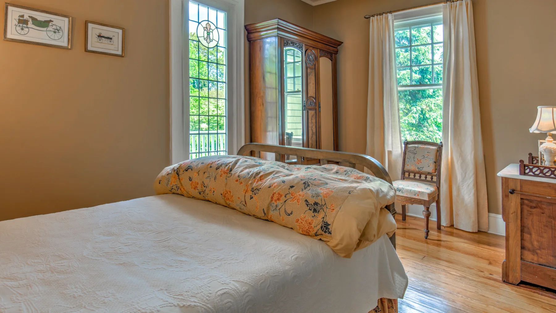 A bedroom with beds, a wooden cabinet, and tall windows.